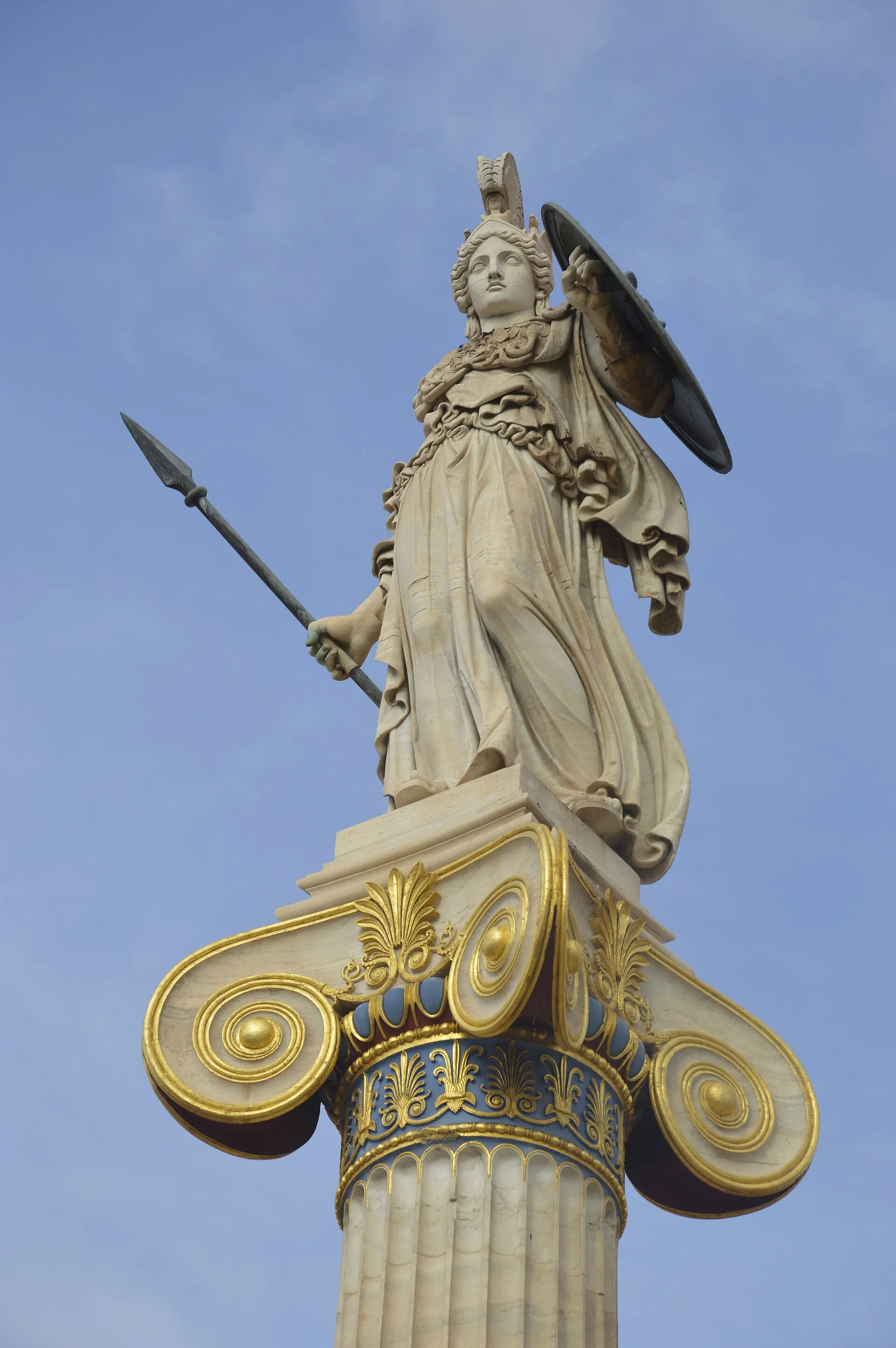Marble statue of Athena on a gilded Ionic column at the Academy of Athens, Greece, against a blue sky — representing knowledge, wisdom, and architectural clarity.